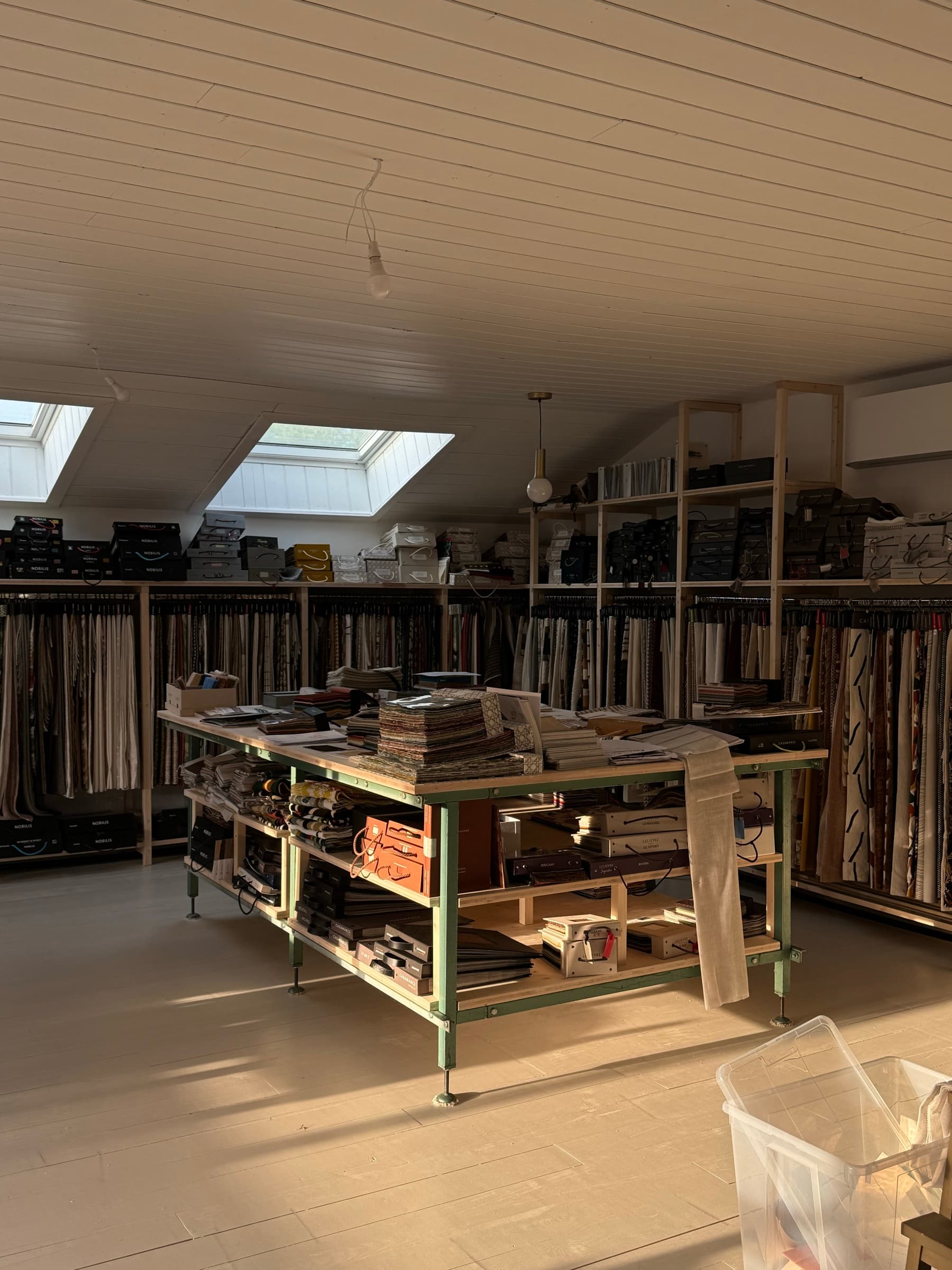 Showroom de l'Atelier Virginie Morel : books de tissus, passementeries et échantillons de matières présentés sur portants